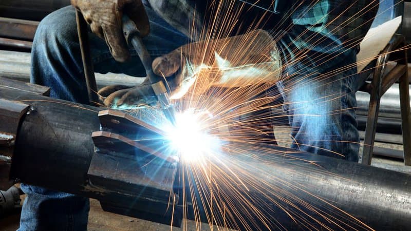 Welder fabricating a structural steel section in the workshop