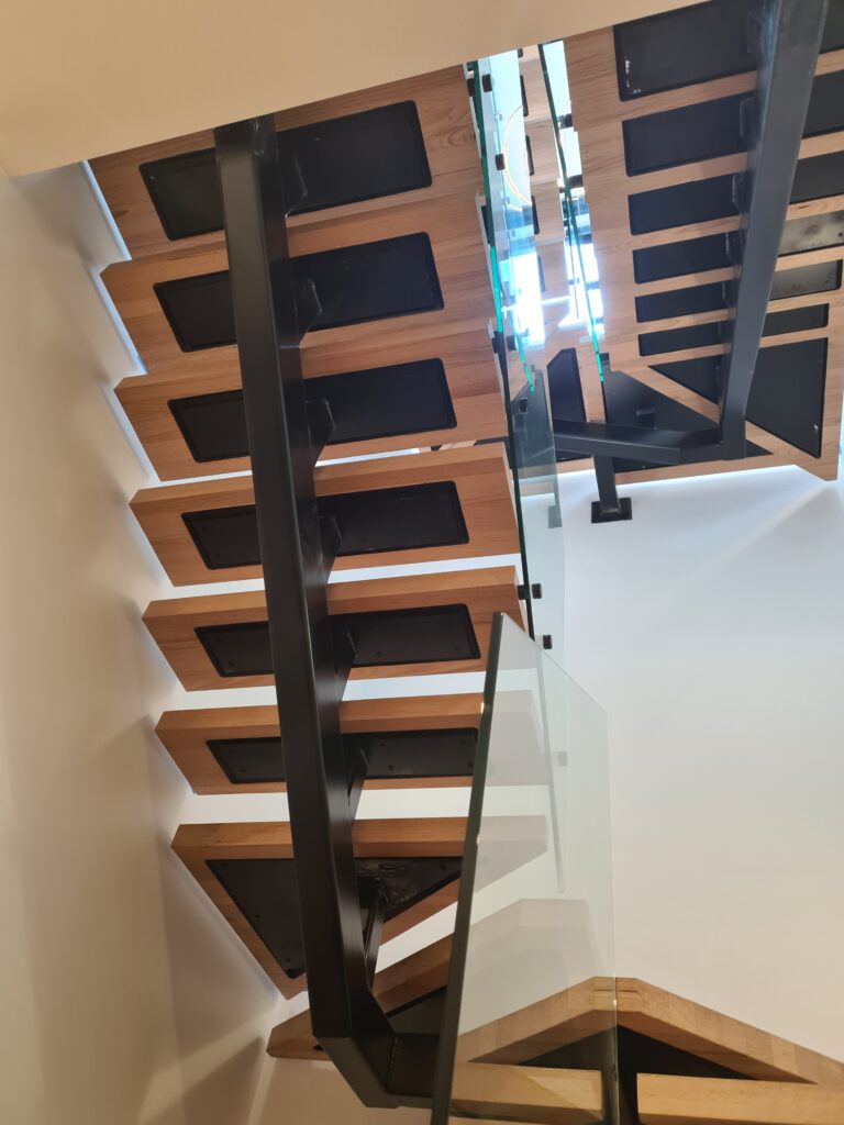 Black steel stair stringers with timber treads and glass balustrade in a multi-level home