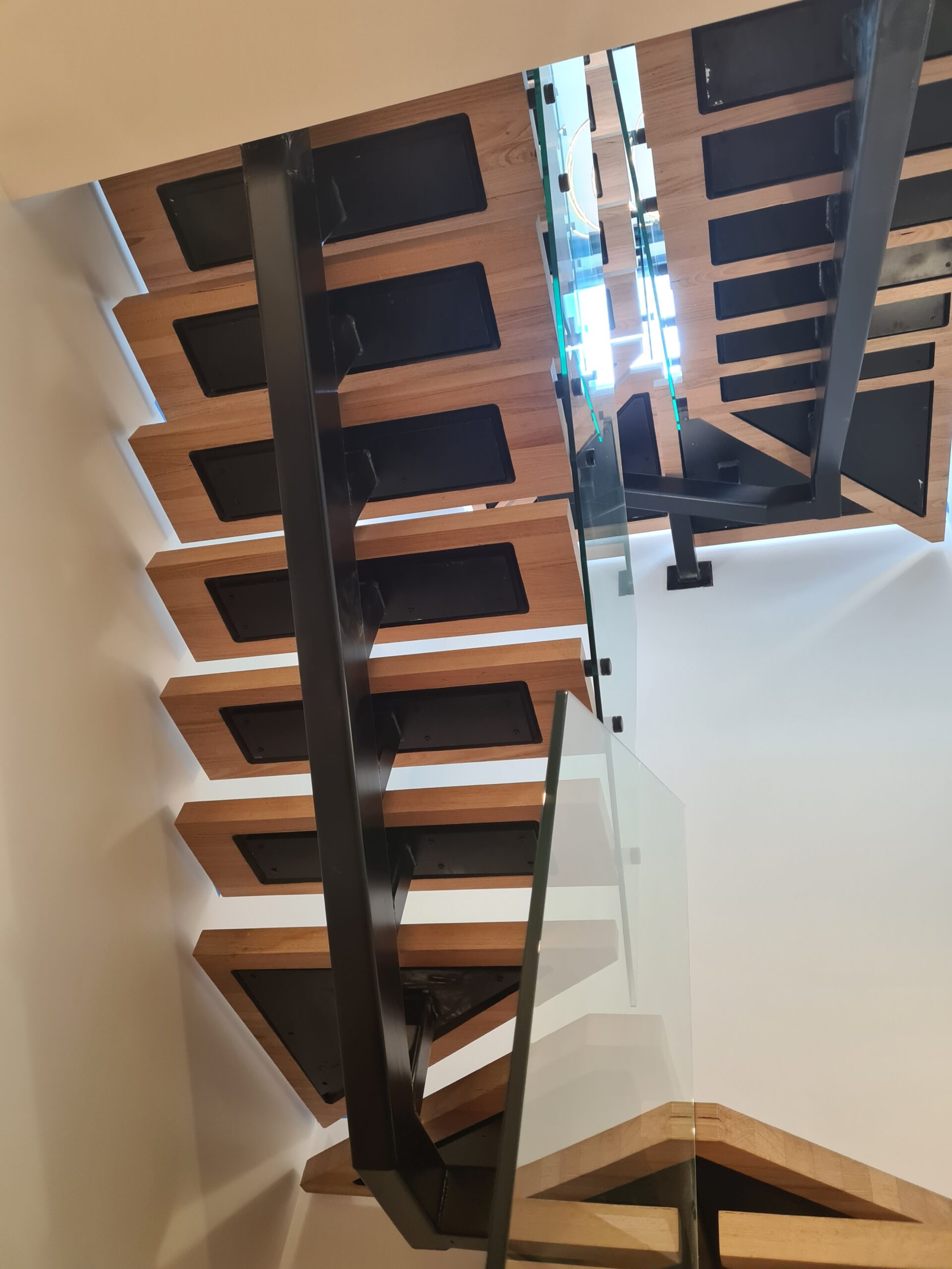 Black steel stair stringers with timber treads and glass balustrade in a multi-level home